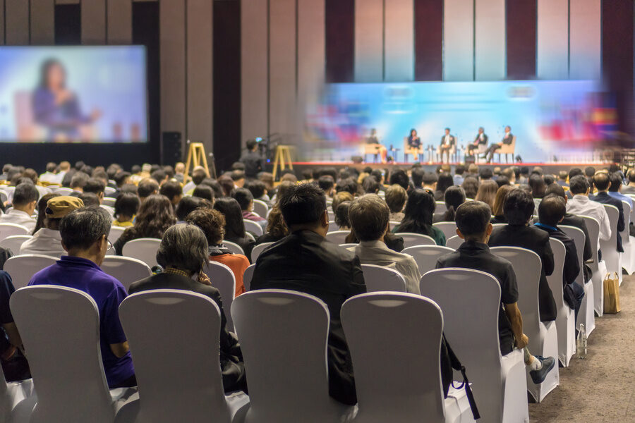 Rear view of Audience listening Speakers on the stage in a corporate event